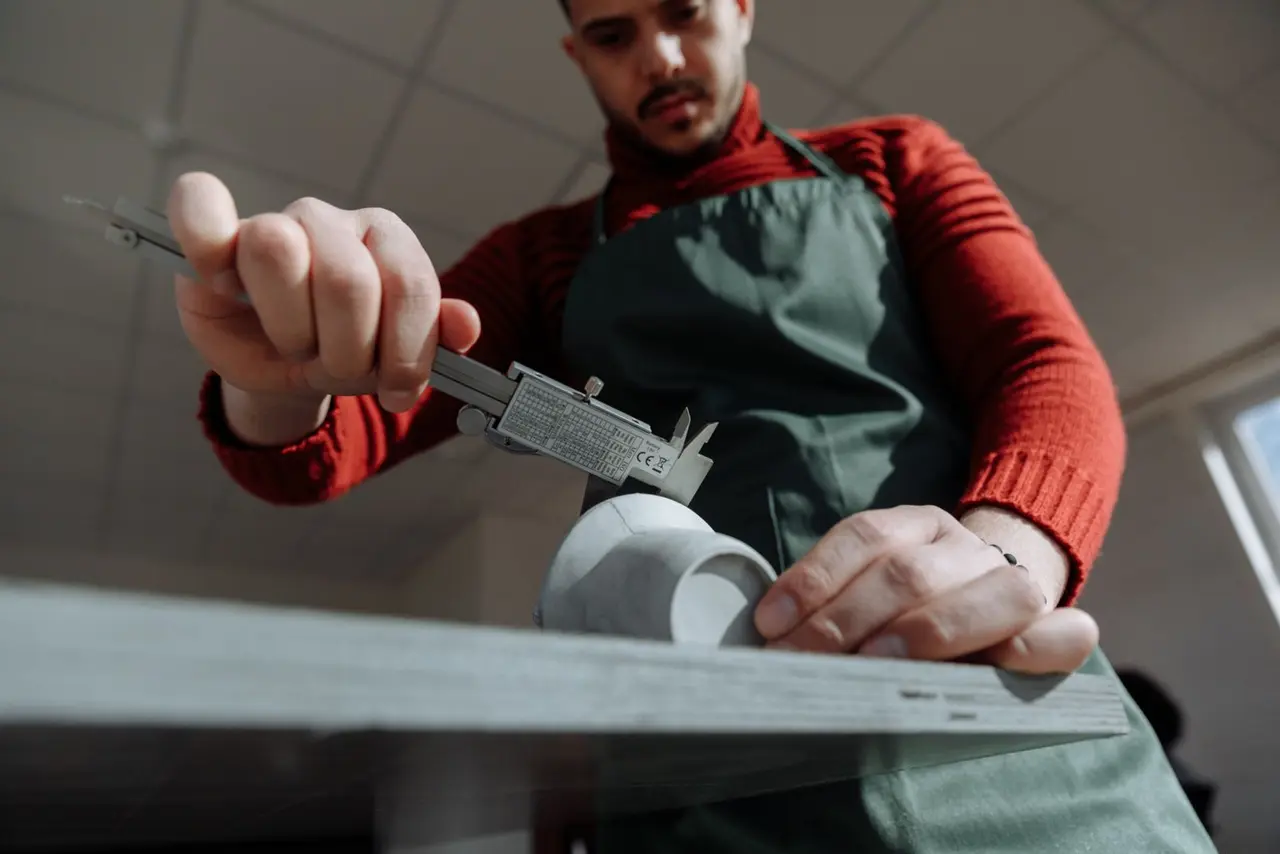 Technician measuring a steel part with a digital caliper